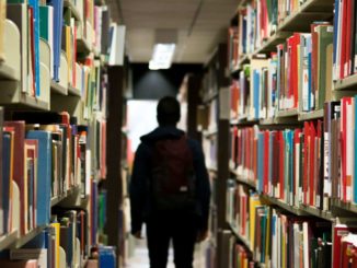 A student walking through bookshelves