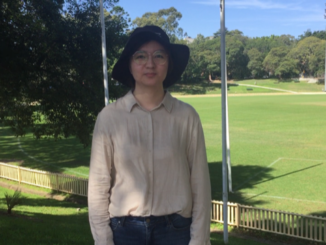 Jiani stands in the shade with a university oval in the background