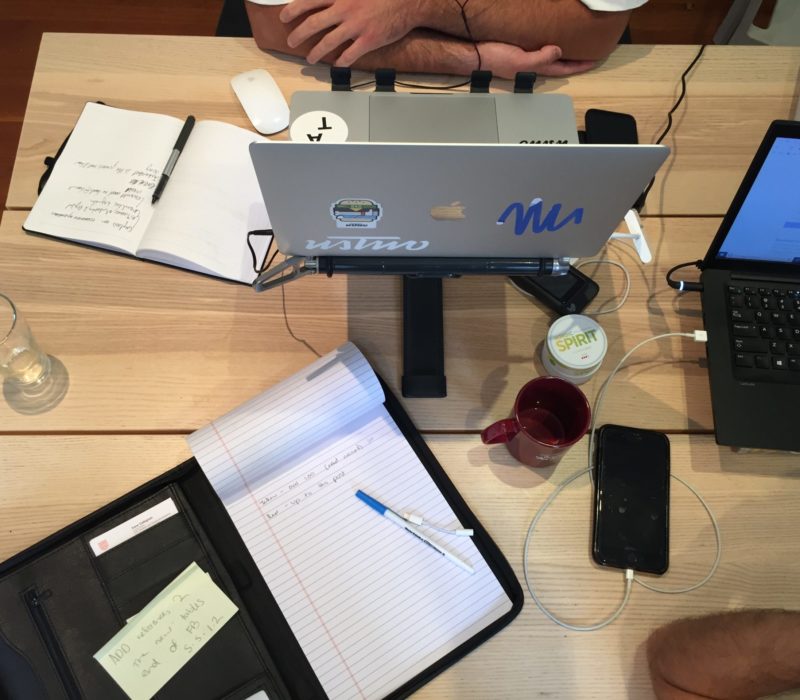 Dining table with note book, laptops, cups with coffee, chargers