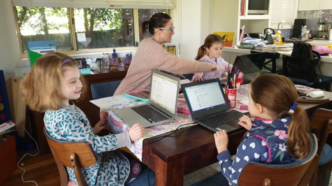 Mother working at home with three kids, all with laptops.